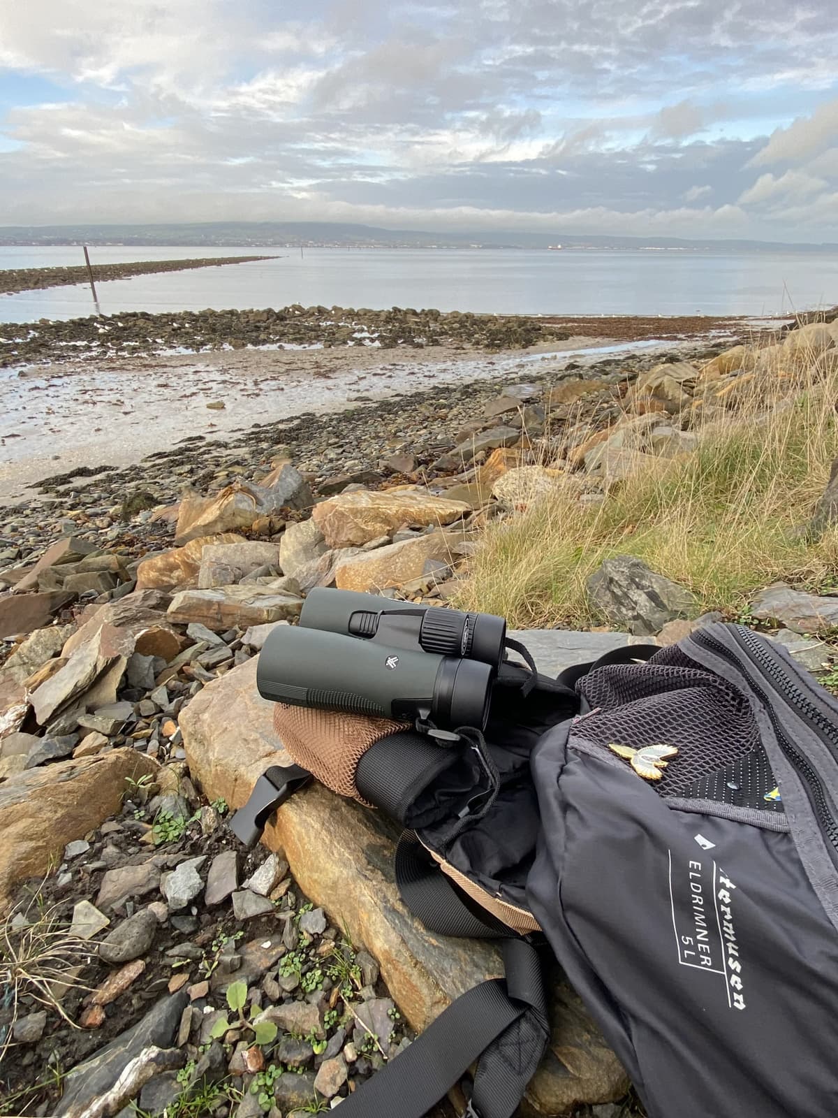 The Vortex Diamondback HD 8x42 binoculars resting on a rock beside the sea